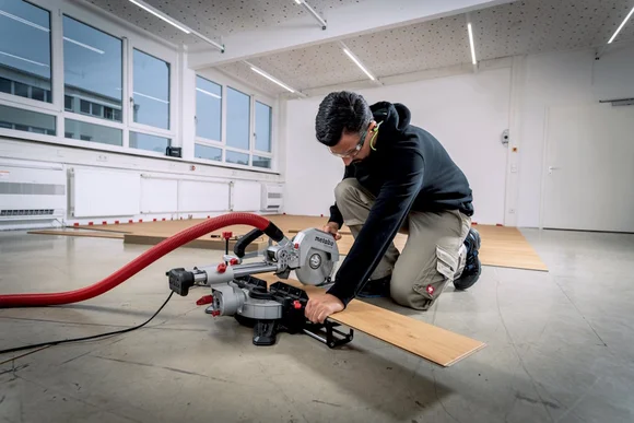 Person sägt Holzbrett mit Kappsäge.